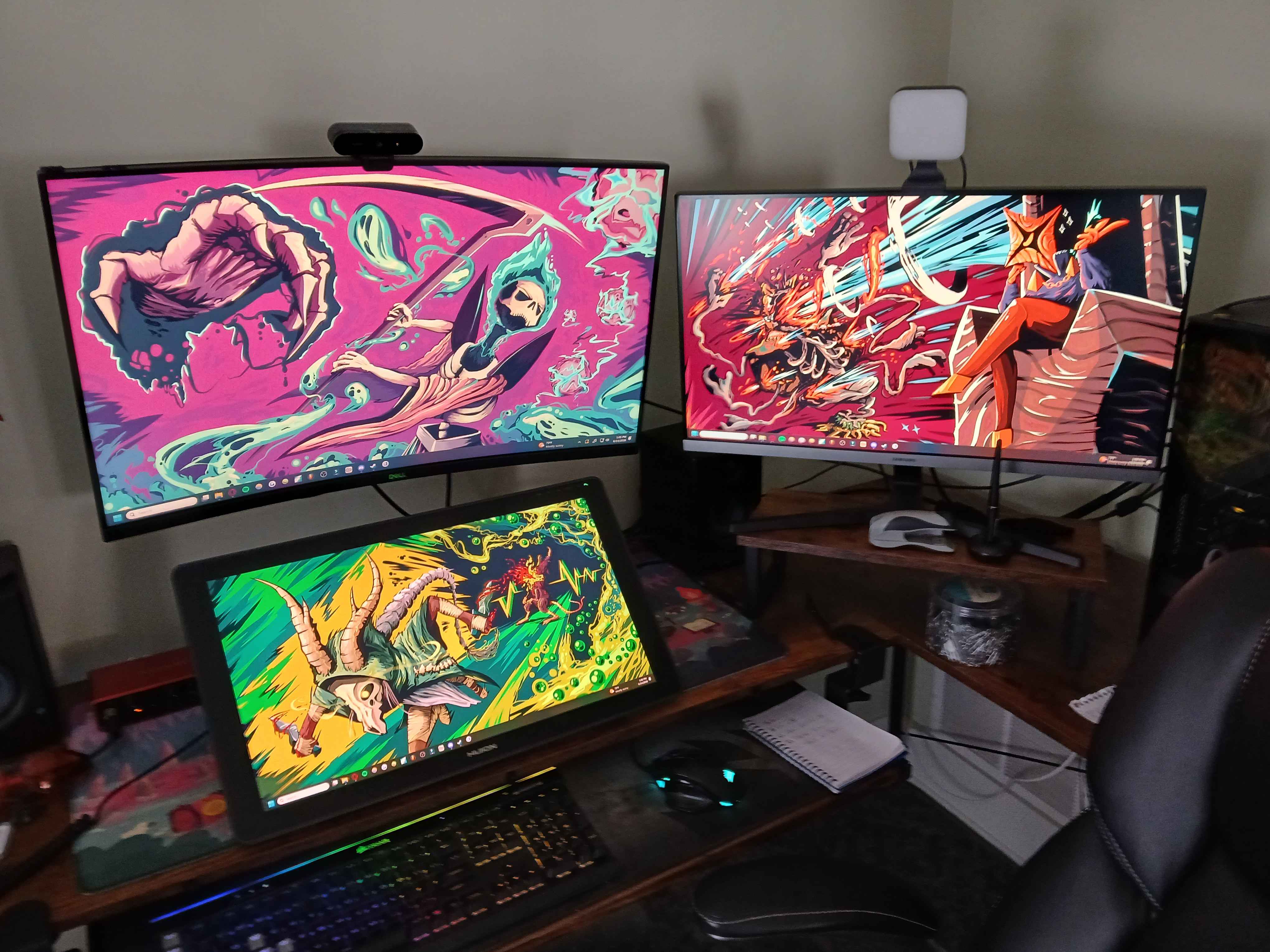 An image of a desk with 2 monitors and a large art tablet, all with backgrounds of boldly colored StS2 fanart.